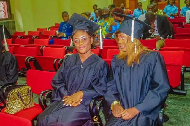 Deux diplômées en toge attendent la remise, dans la salle de cérémonie