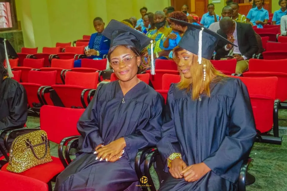 Deux diplômées en toge attendent la remise, dans la salle de cérémonie