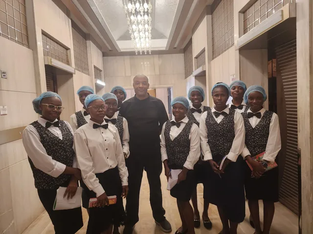 Neuf étudiantes en charlotte autour du chef de cuisine, dans les couloirs de l’hôtel, Fleuve Congo Hotel
