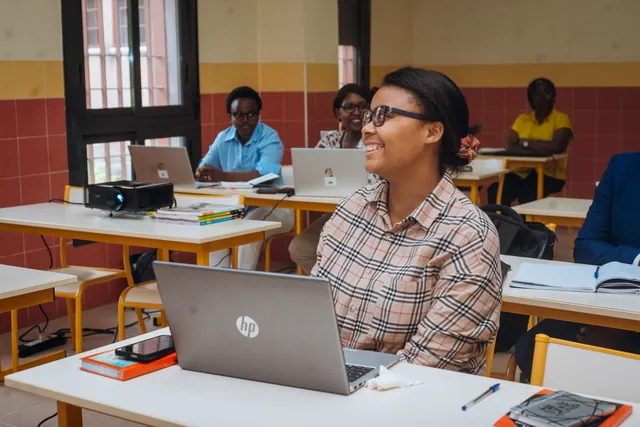 Une enseignante sourit pendant la session de formation, derrière son ordinateur