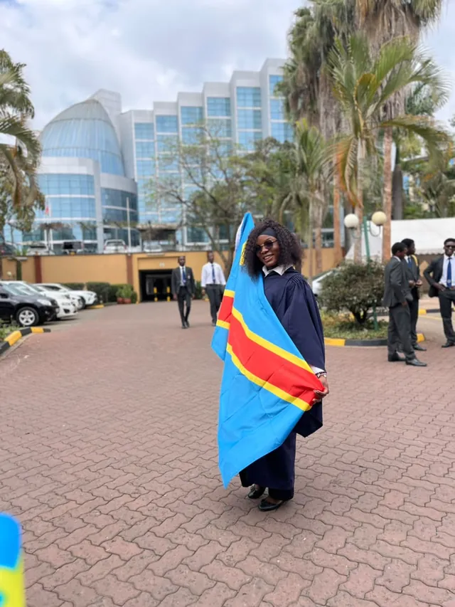 Une diplômée drapée du drapeau congolais devant le centre de formation