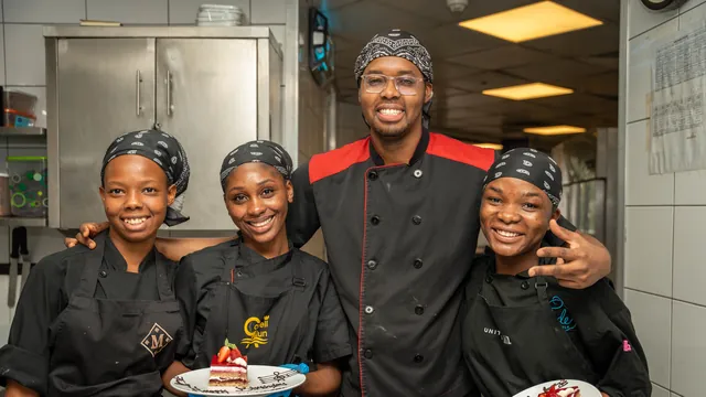 Quatre sourires autour de deux desserts dressés, en cuisine professionnelle