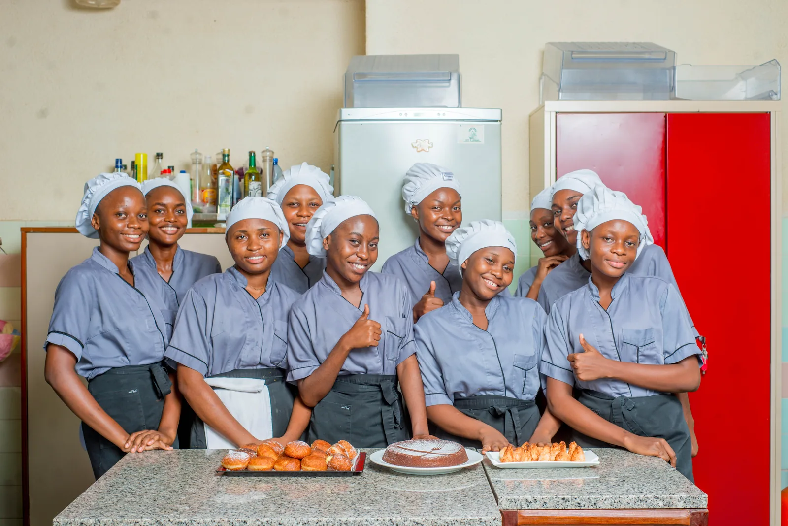 La promotion de deuxième année de Licence en tenue de cuisine, sourire et pouce levé, derrière ses productions