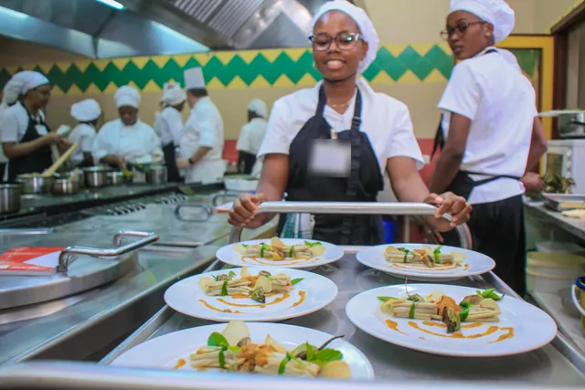 Une étudiante amène les assiettes dressées de la masterclass vers la salle