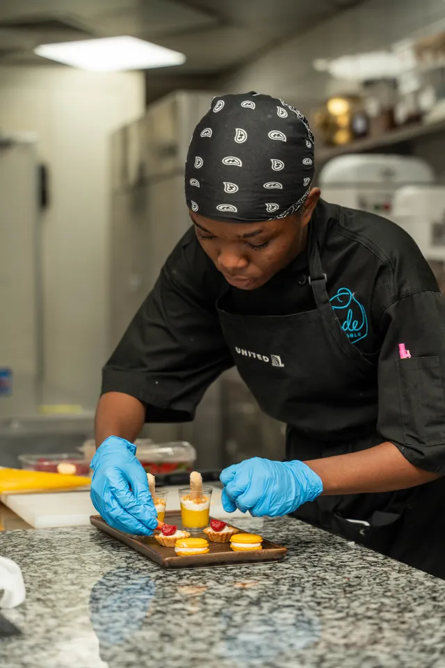 Un étudiant dresse des mignardises à la pince, planche alignée devant lui.