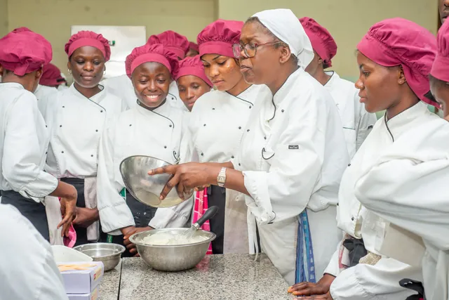 La formatrice montre le geste au groupe, en atelier pâtisserie
