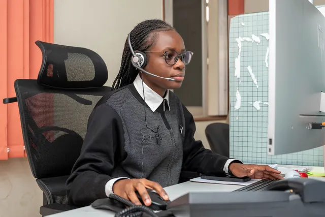 Casque sur les oreilles, une étudiante traite les appels depuis le bureau arrière.