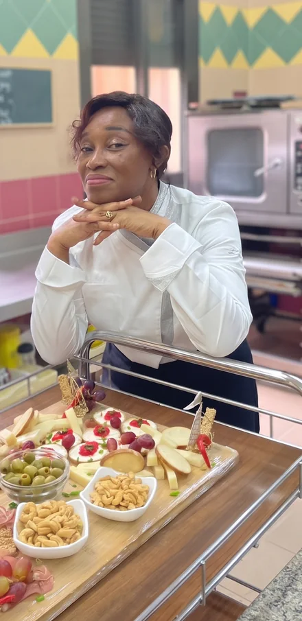 Virginie Lukuichi Nhamba, en veste blanche, accoudée à un plateau de canapés dressé dans la cuisine de l’école.